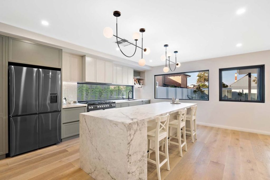 Kitchen with marble waterfall island and globe pendant lights in North Perth