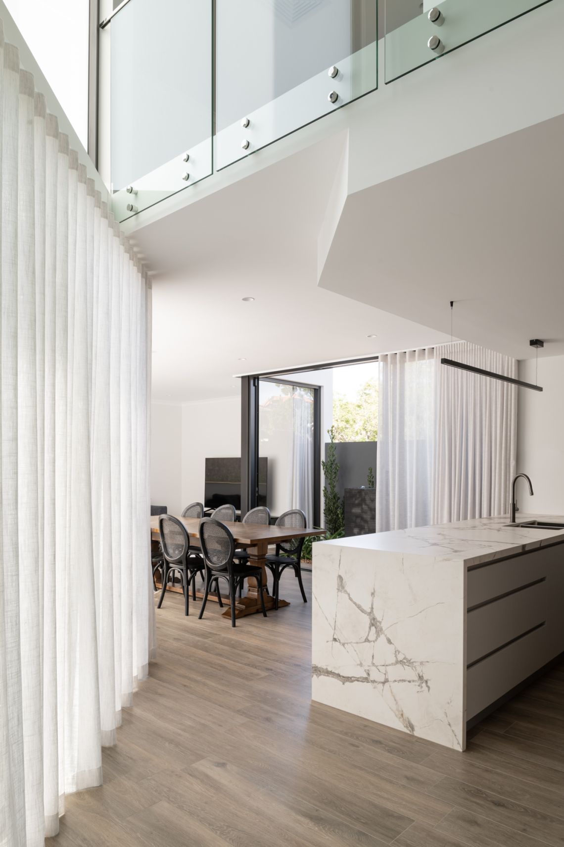 Dining area and marble island under a glass void in Applecross