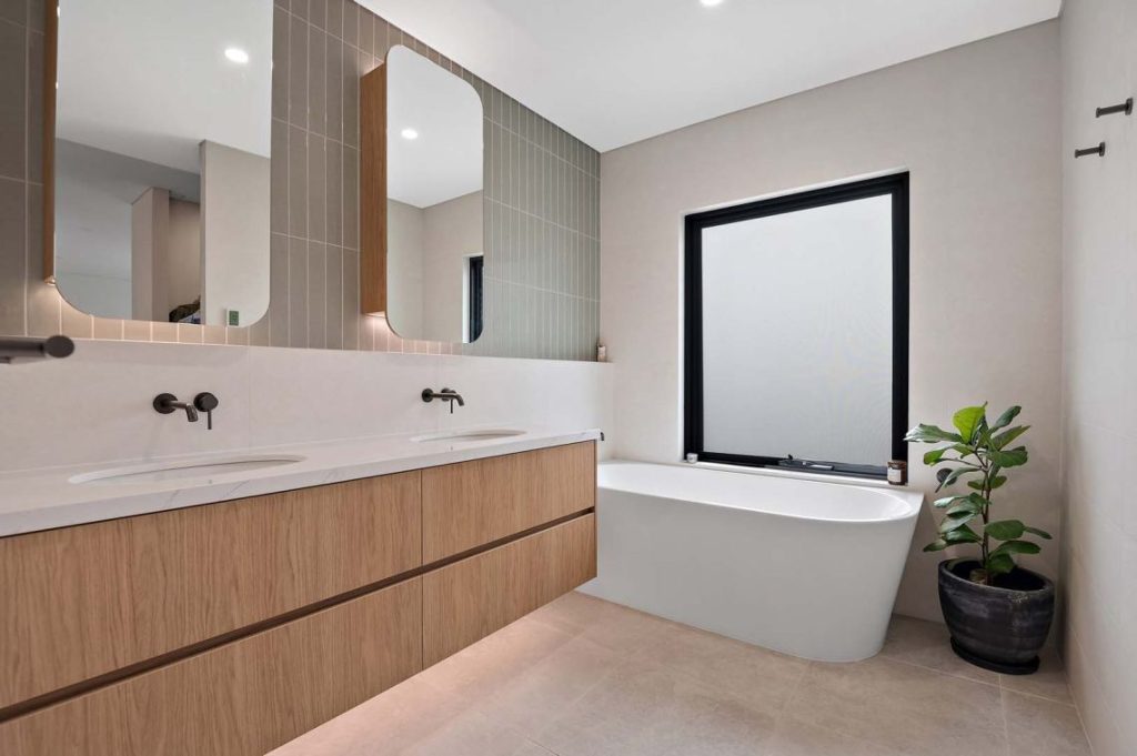 Bathroom with double timber vanity, freestanding bath and backlit mirrors in North Perth