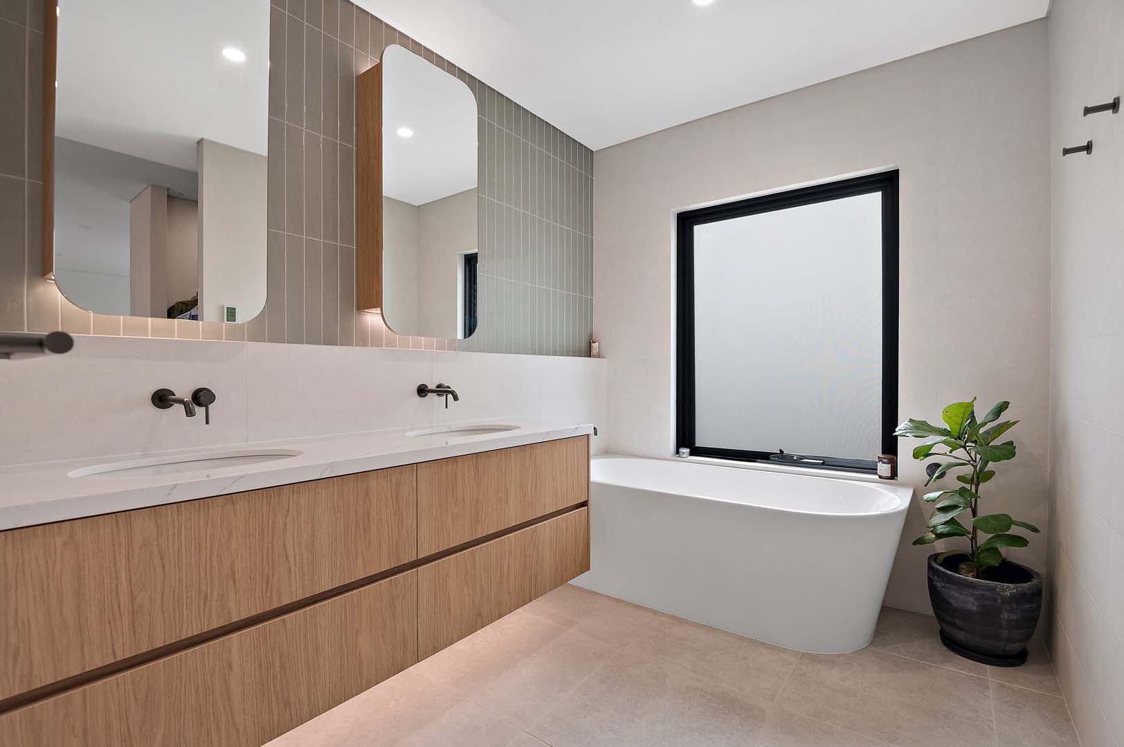 Bathroom with double timber vanity, freestanding bath and backlit mirrors in North Perth
