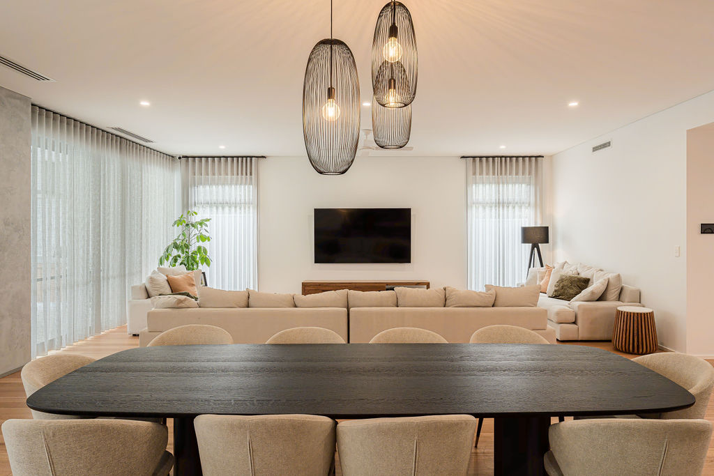 Dining table with cage pendant lights and open plan lounge in Attadale