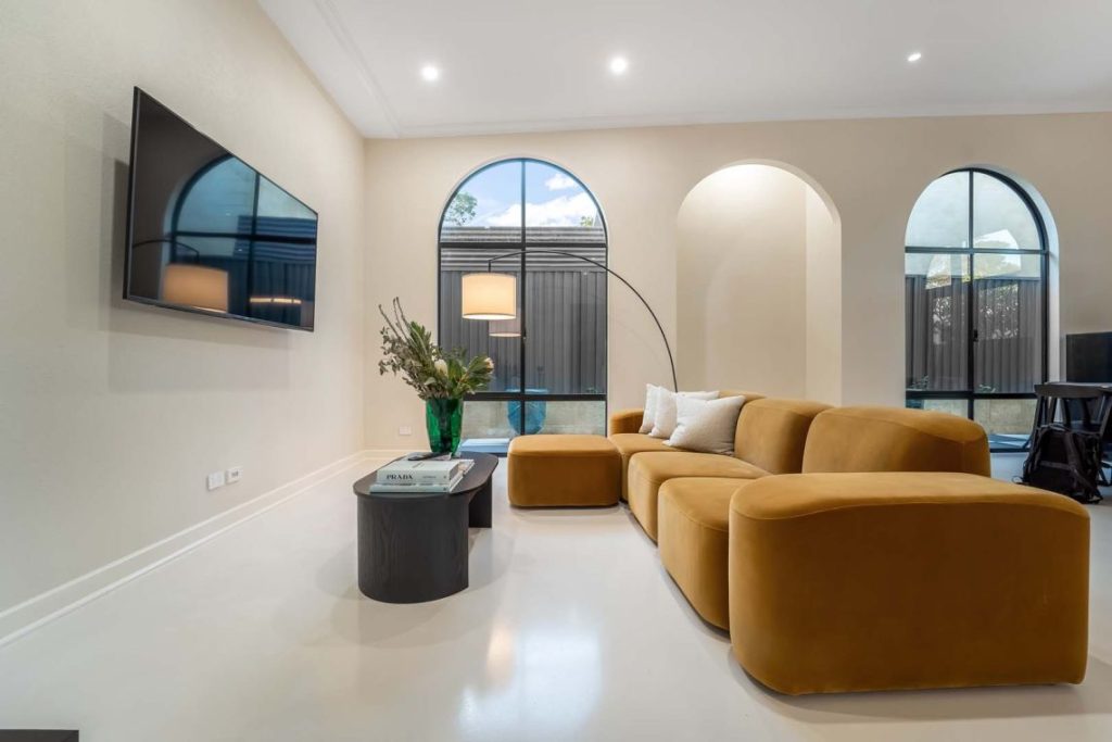 Living room with arched windows and mustard velvet sofa in Fremantle