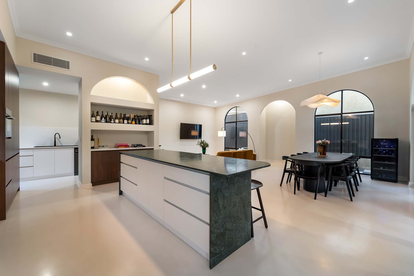 Open plan kitchen with green stone island and arched windows in Fremantle