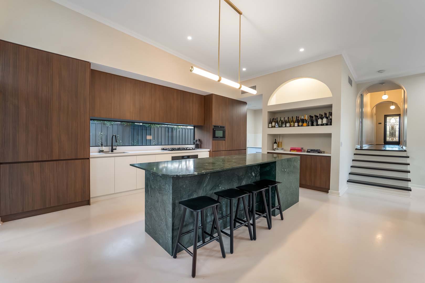 Kitchen with timber cabinetry, green marble island and arched bar niche in Fremantle