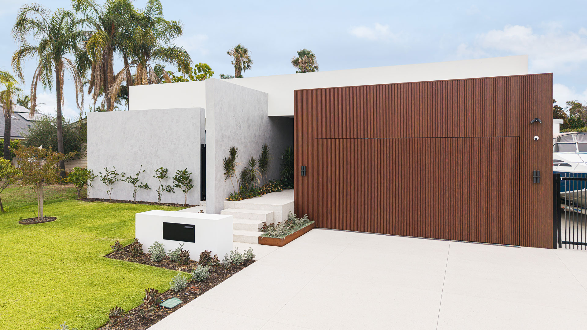 Single storey home with timber clad garage and palm trees in Attadale