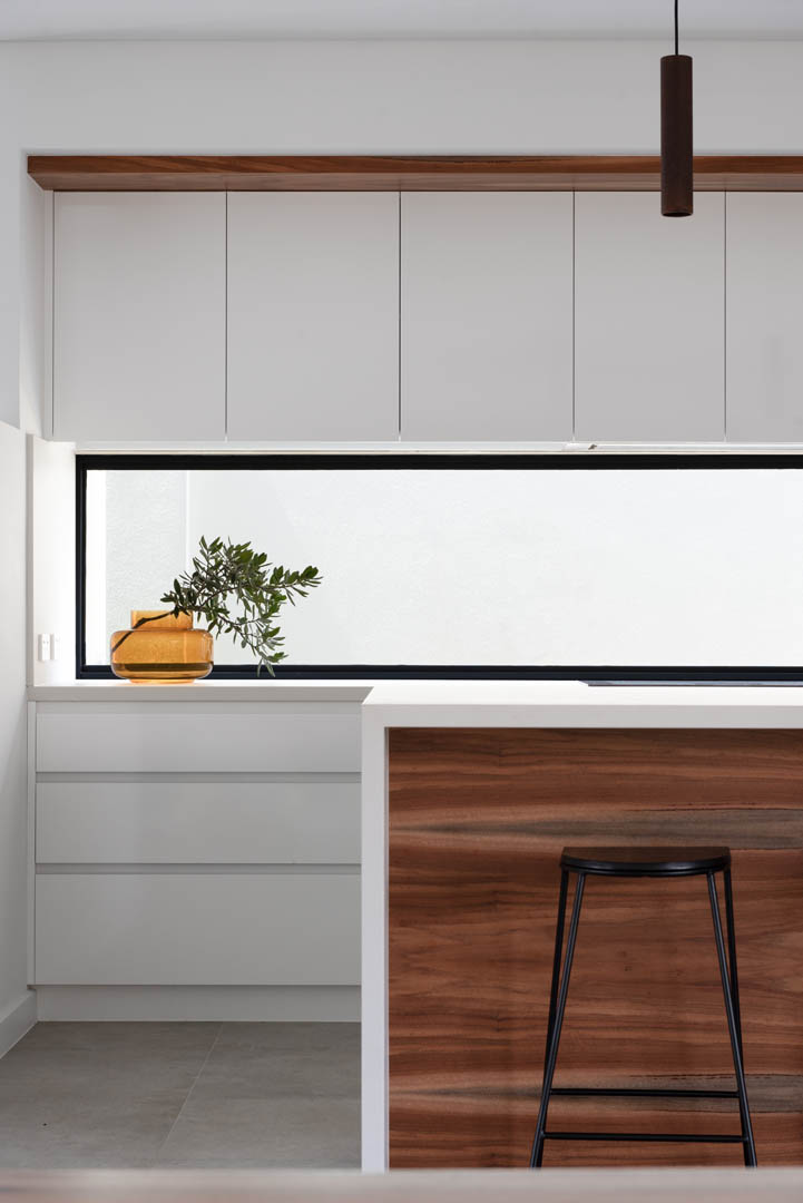 Kitchen with white cabinetry and timber island bench in Mindarie