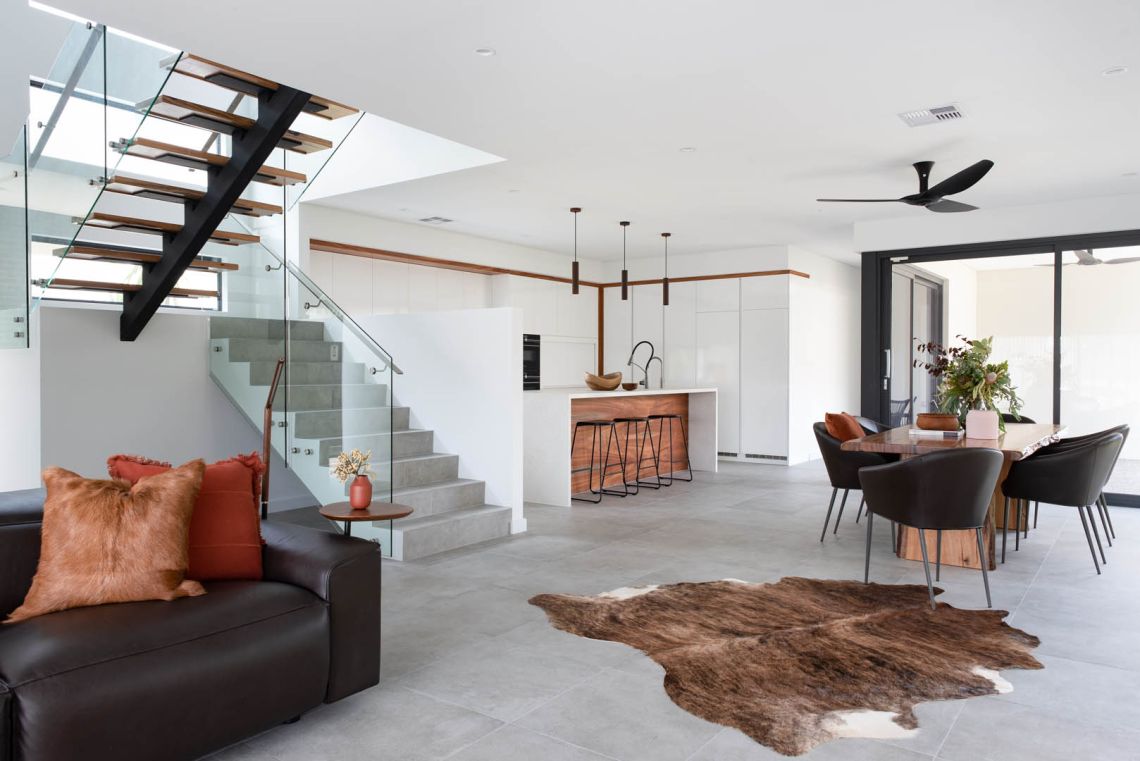 Open plan living with floating staircase and cowhide rug in Mindarie