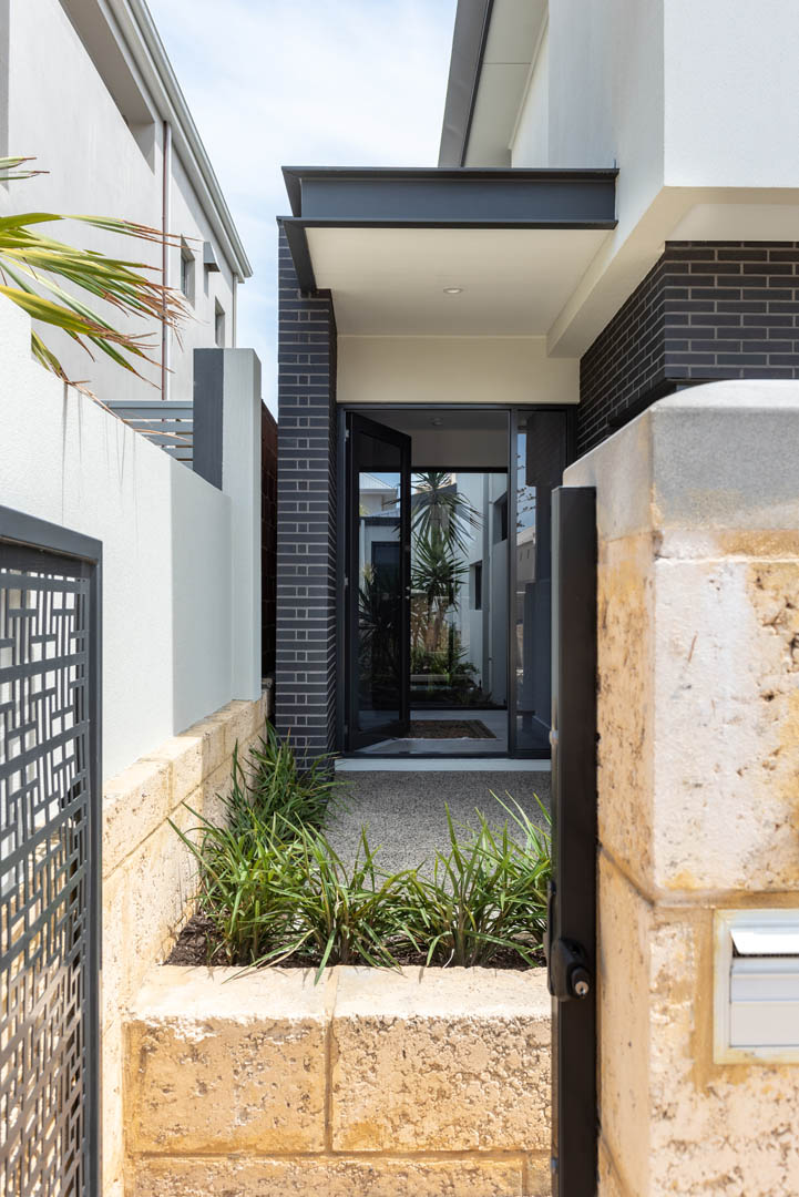 Front entry path with limestone walls and dark brick in Mindarie