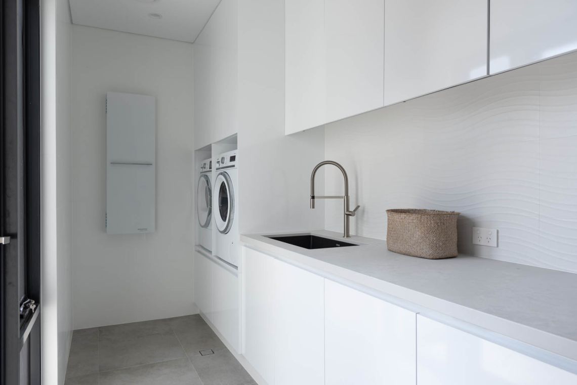 Laundry with white cabinetry and stacked washer and dryer in Mindarie