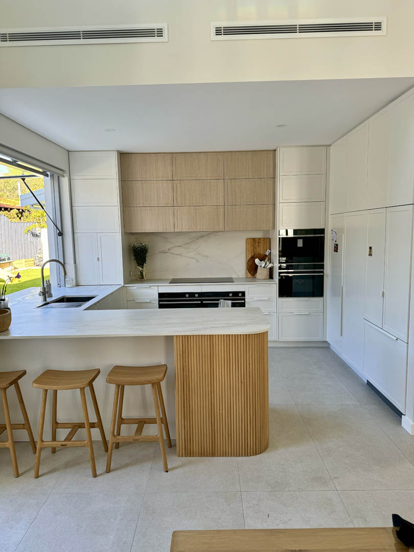 Kitchen with oak overhead cabinets and fluted timber island in City Beach