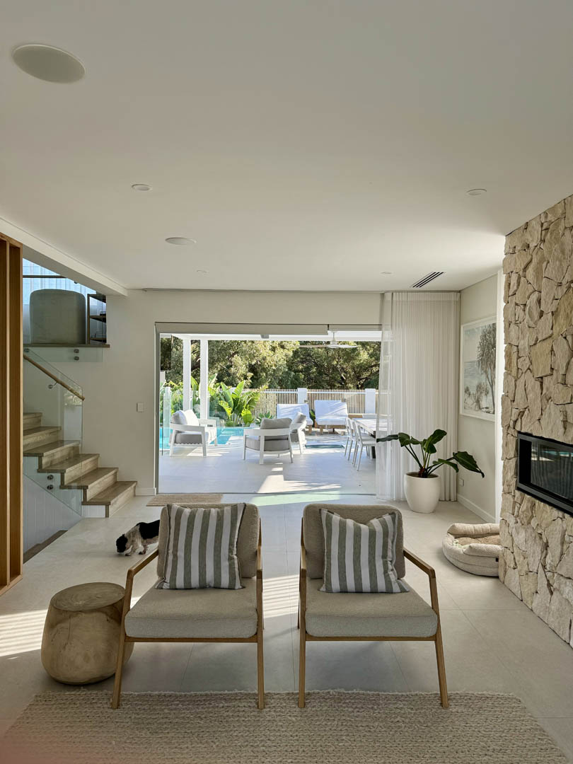 Living room with stone fireplace opening onto the pool terrace in City Beach