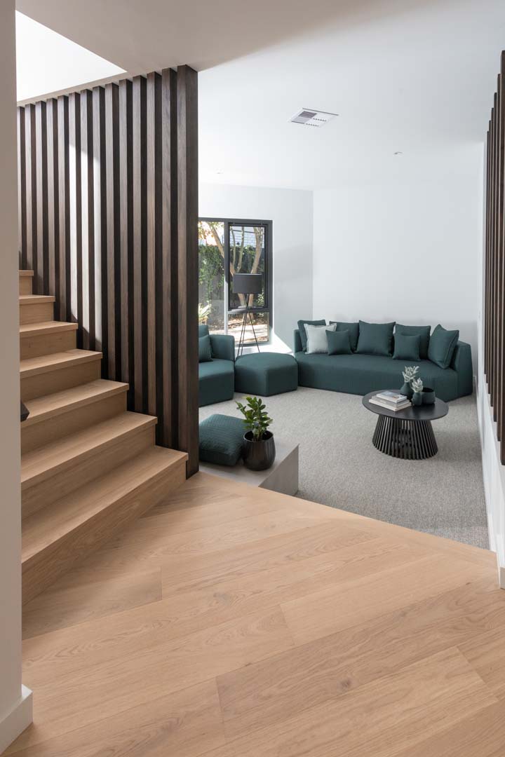 Sunken lounge with green modular sofa beside timber stairs in Floreat