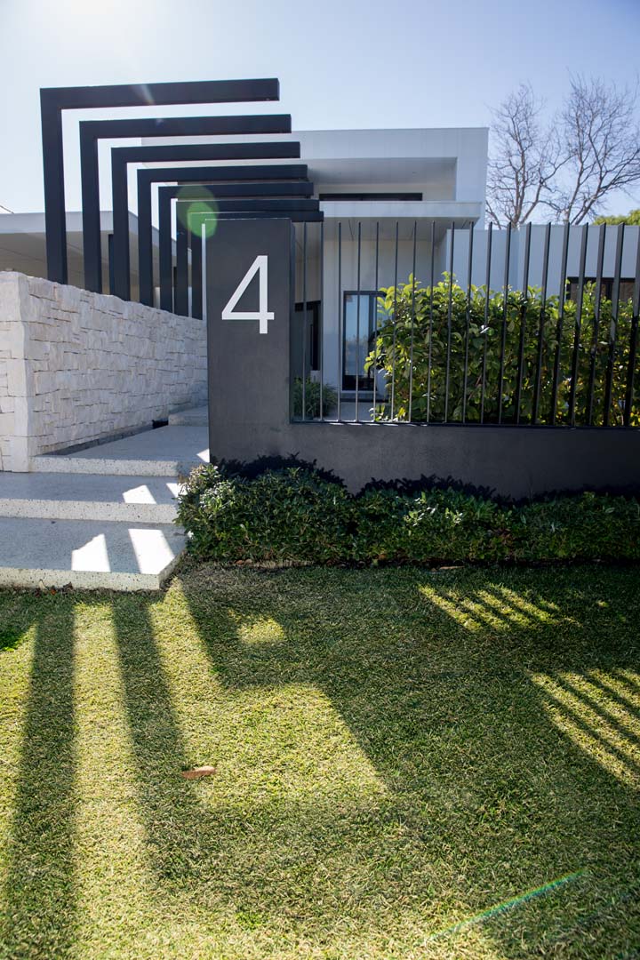 Black steel pergola and stone wall at the front entry in Floreat