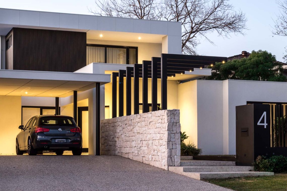 Carport and stacked stone wall of a modern home at dusk in Floreat