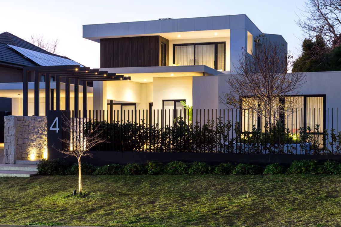 Two storey modern home with pergola and slatted fence at dusk in Floreat