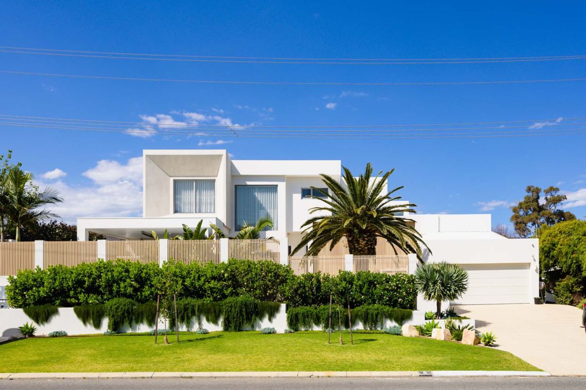 White two storey home with palm tree and landscaped front garden in City Beach