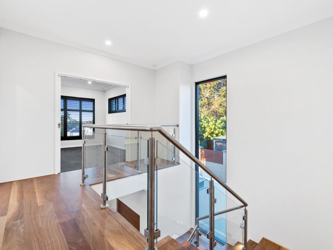 Upstairs landing with glass balustrade and timber stairs in Tuart Hill