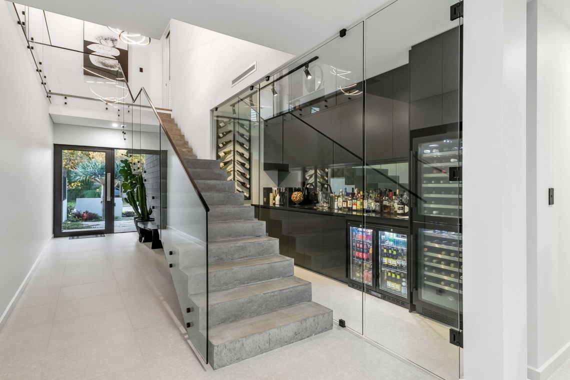 Floating concrete staircase beside a glass wine cellar in Attadale